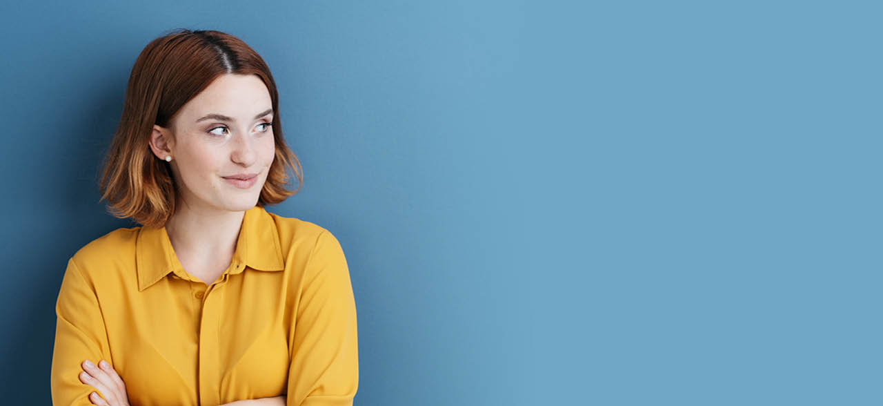 eine Frau in einem gelben Hemd, die gegen eine blaue Wand steht