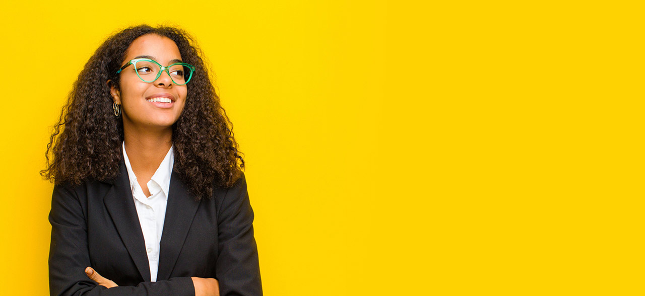 eine Frau in einem Anzug und Brille, die mit gekreuzten Armen steht