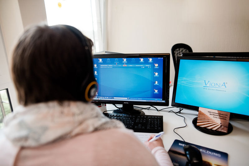 eine Frau, die an einem Schreibtisch mit zwei Computermonitoren sitzt