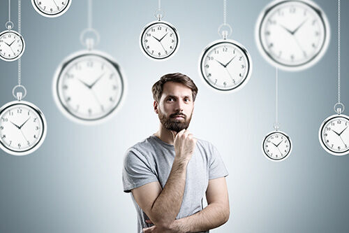 ein Mann, der vor einer Wand mit Uhren steht