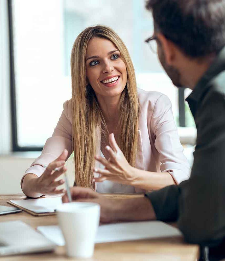 eine Frau und ein Mann, die an einem Tisch sitzen und reden