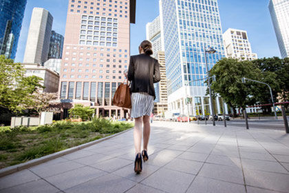 eine Frau, die in einer Stadt einen Bürgersteig hinuntergeht