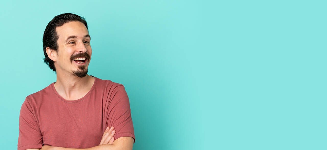 ein Mann mit Bart und einem rosa Hemd lächelt zur Kamera